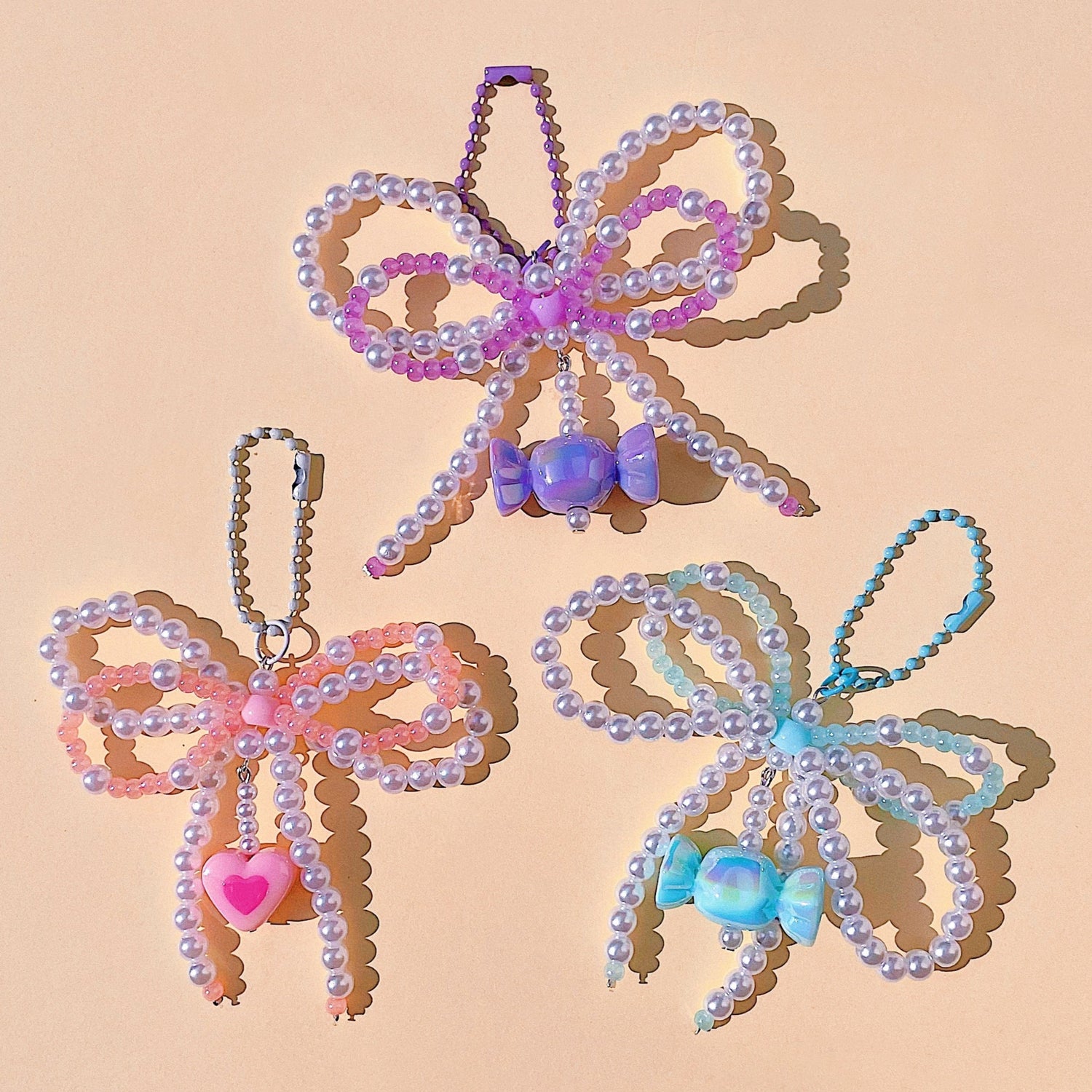 Three decorative bow-shaped objects with beads on a beige background